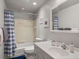 This bathroom features a clean and functional design with a bathtub and shower combination, complemented by a blue and white striped shower curtain.