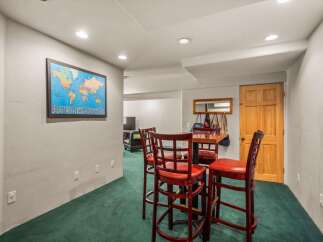 This basement living area features a cozy bar with four red stools, perfect for casual dining or entertaining.