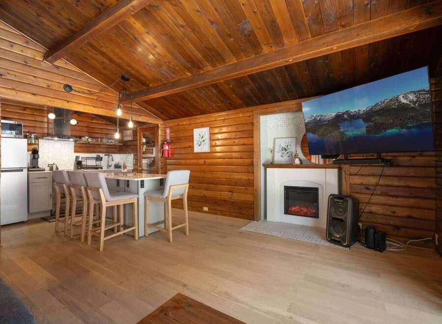 Experience rustic charm in this cozy log cabin featuring a modern kitchen island with bar seating, perfect for casual dining.