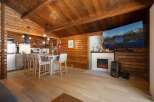 Experience rustic charm in this cozy log cabin featuring a modern kitchen island with bar seating, perfect for casual dining.