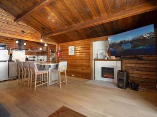 Experience rustic charm in this cozy log cabin featuring a modern kitchen island with bar seating, perfect for casual dining.