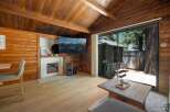 Experience cozy cabin living with this charming interior featuring a modern electric fireplace and a large flat-screen TV mounted on wood-paneled walls.