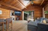 Experience rustic charm in this cozy cabin living room, featuring a vaulted wood-paneled ceiling and a large stone fireplace.