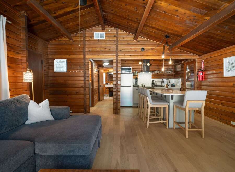 Experience rustic charm in this beautifully appointed cabin, featuring a spacious living area with a comfortable sectional sofa and a modern kitchen with a breakfast bar.
