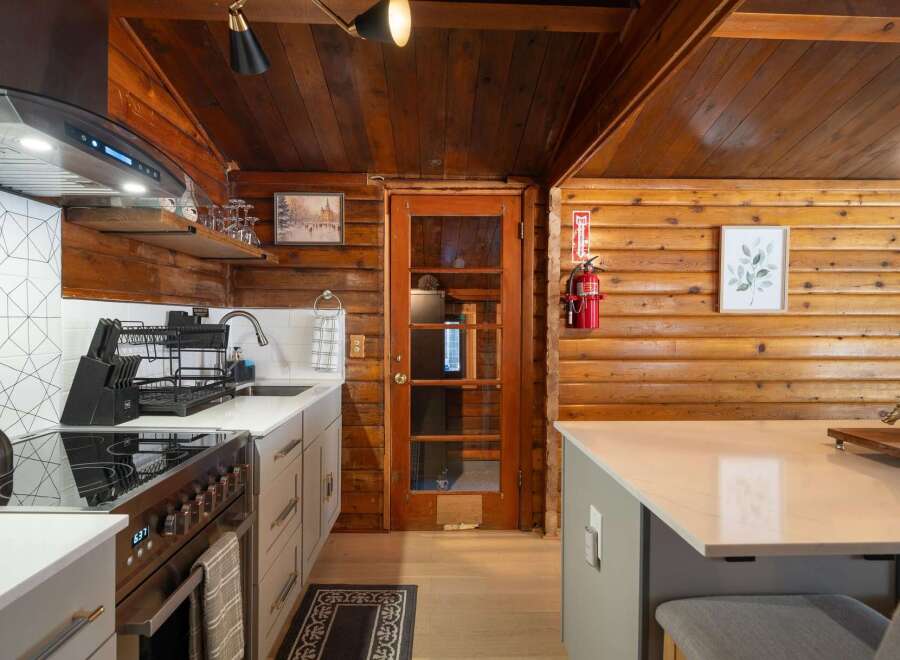 Experience rustic charm in this cozy kitchen featuring warm wood paneling and a modern aesthetic.