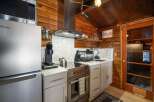 Experience cozy living in this charming cabin kitchen, featuring a sleek stainless steel refrigerator and a modern induction stovetop.