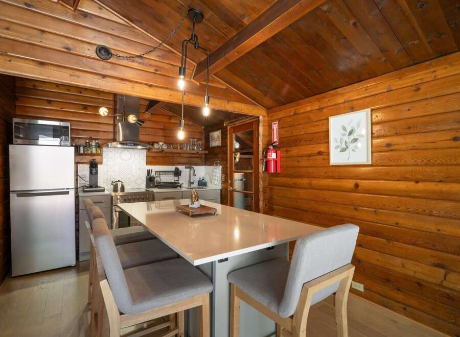 Experience rustic charm in this cozy cabin kitchen, featuring warm wood paneling and a modern island with seating.