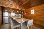 Experience rustic charm in this cozy cabin kitchen, featuring warm wood paneling and a modern island with seating.