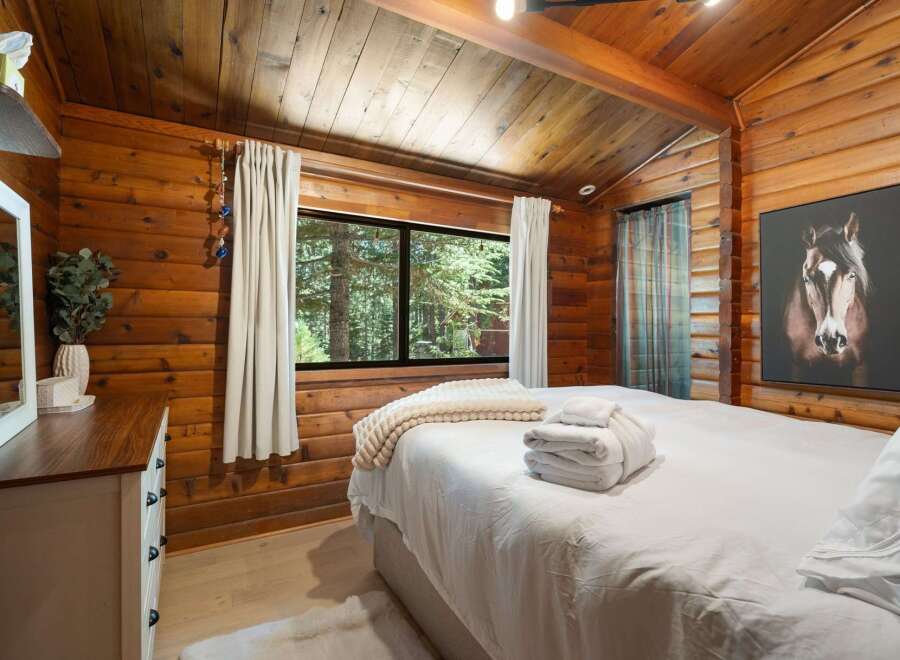 Experience rustic charm in this cozy bedroom featuring warm wood paneling and a vaulted ceiling with exposed beams.
