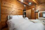 Experience rustic charm in this cozy bedroom, featuring warm wood-paneled walls and a comfortable bed with crisp white linens.