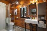 Experience rustic charm in this beautifully appointed bathroom, featuring warm wood paneling and a modern glass shower enclosure.