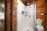 Experience rustic charm in this unique bathroom featuring a modern glass-enclosed shower with multiple dispensers and sleek shelving.