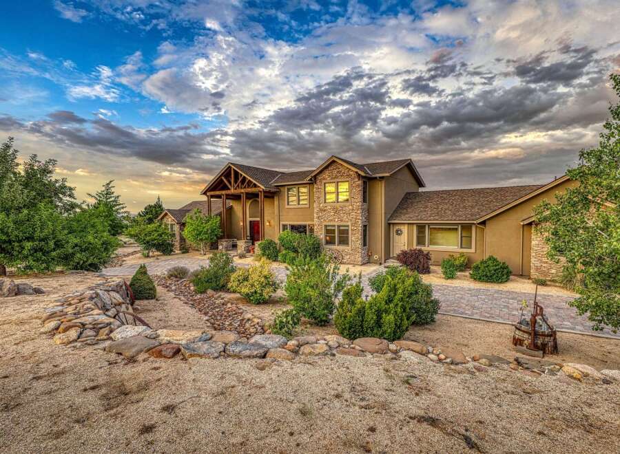 Discover this stunning custom-built home featuring a striking stone facade and a grand covered entryway.