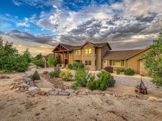 Discover this stunning custom-built home featuring a striking stone facade and a grand covered entryway.