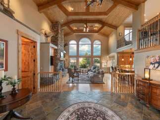 Experience luxury living in this grand lodge-style home featuring a soaring vaulted ceiling with exposed beams and a magnificent stone fireplace.