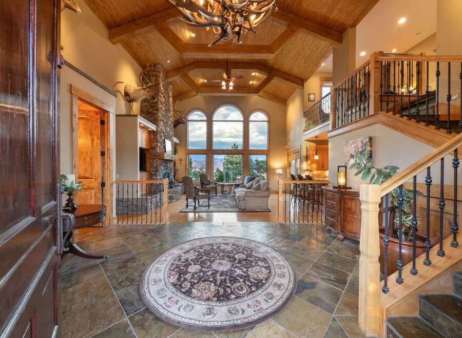 Step into this grand entryway featuring a stunning stone fireplace and vaulted wood-beamed ceilings.