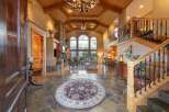 Step into this grand entryway featuring a stunning stone fireplace and vaulted wood-beamed ceilings.