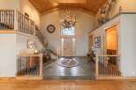 Step into this grand entryway featuring a stunning antler chandelier and a rustic wooden door, complemented by a beautiful slate tile floor and a circular area rug.