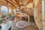 Step into this grand entryway featuring a stunning antler chandelier and soaring vaulted ceilings with exposed wood beams.