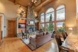 Experience breathtaking mountain views from this stunning living room, featuring a grand stone fireplace and soaring vaulted ceilings with exposed wooden beams.