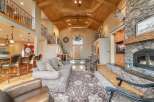 Experience rustic elegance in this grand living room, featuring a soaring vaulted ceiling with exposed wooden beams and a magnificent antler chandelier.