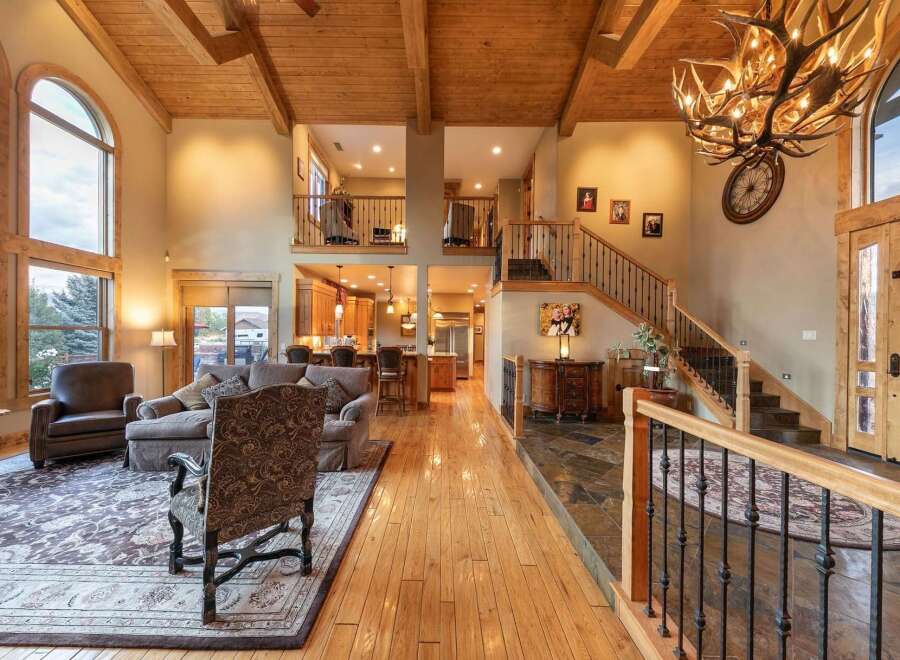 Experience luxurious living in this grand lodge-style home, featuring soaring vaulted ceilings with exposed wooden beams and a stunning antler chandelier.