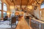 Experience luxurious living in this grand lodge-style home, featuring soaring vaulted ceilings with exposed wooden beams and a stunning antler chandelier.
