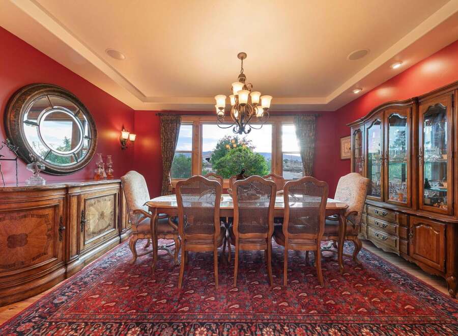Experience elegant dining in this formal dining room, featuring a stunning red accent wall and a large, ornate rug.