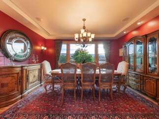 Experience elegant dining in this formal dining room, featuring a stunning red accent wall and a large, ornate rug.