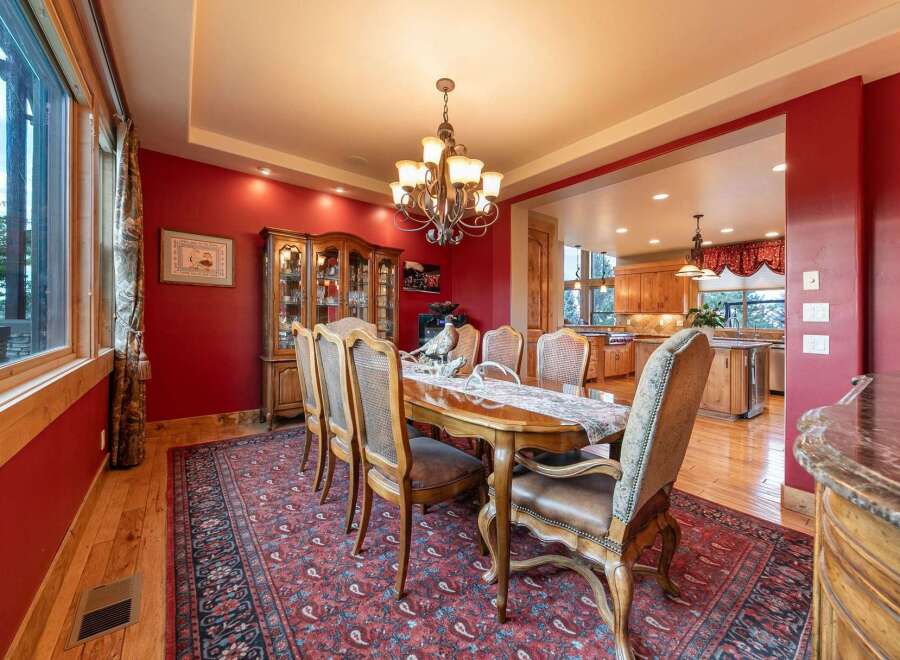 Experience elegant dining in this stunning room featuring a large wooden dining table set for a feast, complemented by a traditional chandelier and a beautiful display cabinet.