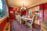 Experience elegant dining in this stunning room featuring a large wooden dining table set for a feast, complemented by a traditional chandelier and a beautiful display cabinet.