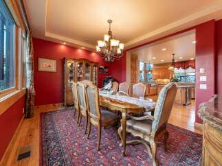 Experience elegant dining in this stunning room featuring a large wooden dining table set for a feast, complemented by a traditional chandelier and a beautiful display cabinet.