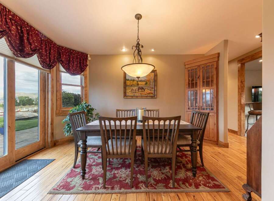 Experience elegant dining in this charming room, featuring a rustic wooden table and chairs set on a beautiful floral rug.
