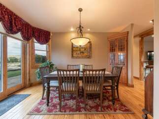 Experience elegant dining in this charming room, featuring a rustic wooden table and chairs set on a beautiful floral rug.