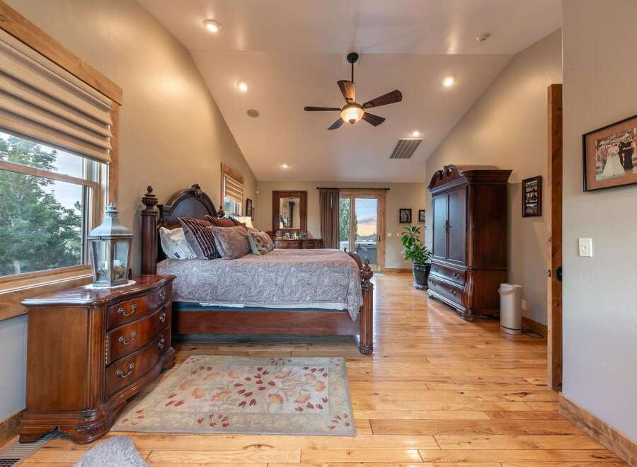 Experience luxury in this spacious master bedroom, featuring a grand wooden bed with plush pillows and a patterned comforter.