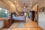 Experience luxury in this spacious master bedroom, featuring a grand wooden bed with plush pillows and a patterned comforter.