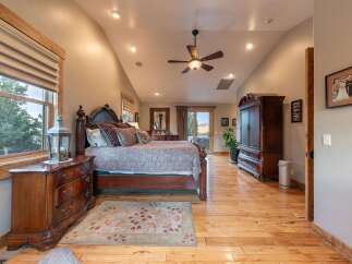 Experience luxury in this spacious master bedroom, featuring a grand wooden bed with plush pillows and a patterned comforter.