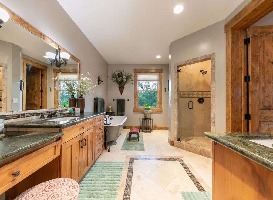Experience luxury in this spacious master bathroom, featuring a freestanding soaking tub and a separate glass-enclosed shower with elegant tilework.