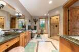 Experience luxury in this spacious master bathroom, featuring a freestanding soaking tub and a separate glass-enclosed shower with elegant tilework.