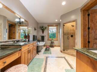 Experience luxury in this spacious master bathroom, featuring a freestanding soaking tub and a separate glass-enclosed shower with elegant tilework.