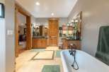 Experience luxury in this spacious bathroom featuring dual vanities with rich wooden cabinetry and granite countertops.