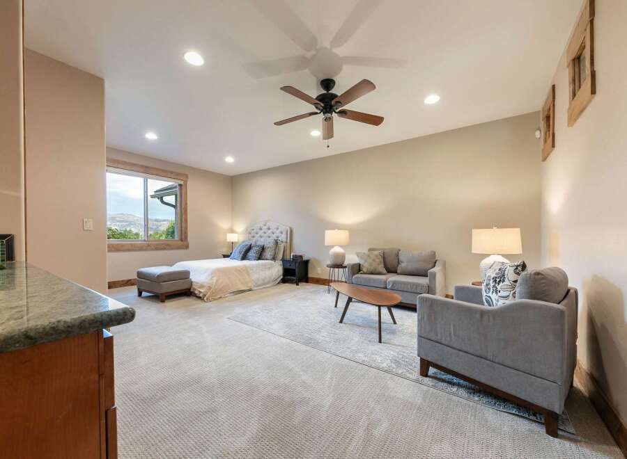Experience luxury living in this spacious master suite, featuring a plush king-sized bed with a tufted headboard and a cozy seating area.