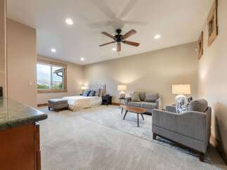 Experience luxury living in this spacious master suite, featuring a plush king-sized bed with a tufted headboard and a cozy seating area.