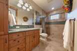 This charming bathroom features a custom wood vanity with a granite countertop, complemented by a tiled backsplash and a large mirror.