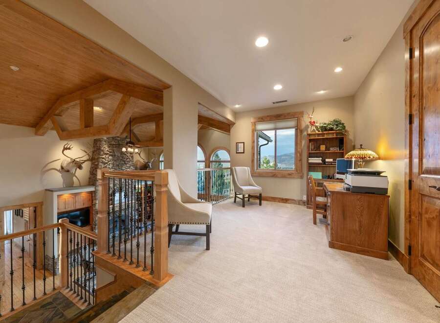 Experience rustic elegance in this spacious home featuring a grand staircase with intricate railings and exposed wooden beams.