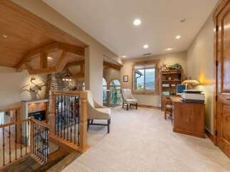 Experience rustic elegance in this spacious home featuring a grand staircase with intricate railings and exposed wooden beams.