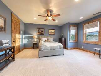Experience rustic charm in this inviting bedroom, featuring a plush king-sized bed with a tufted headboard and elegant patterned bedding.