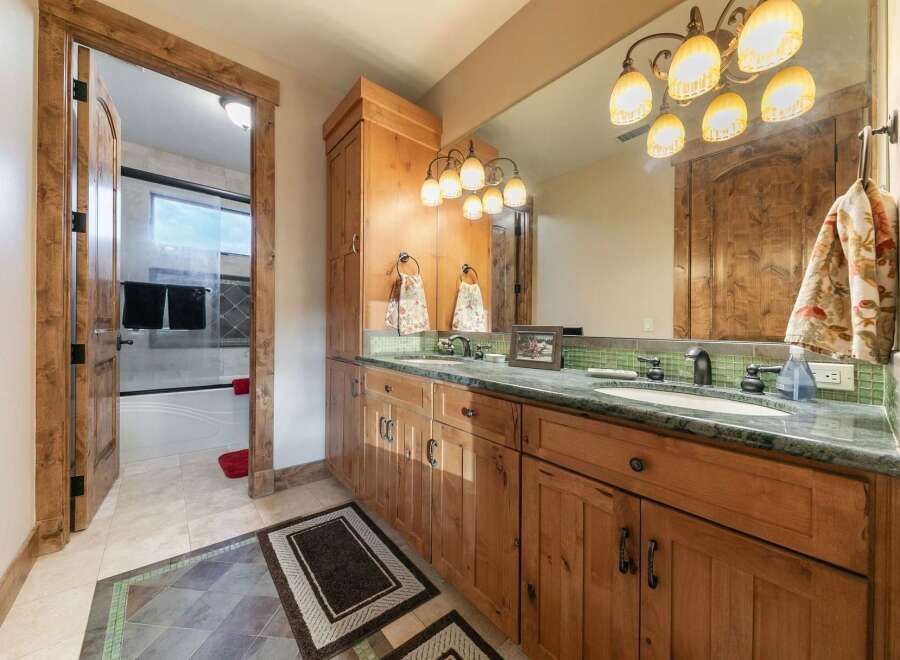 Experience rustic elegance in this charming bathroom, featuring a double vanity with a granite countertop and warm wood cabinetry.