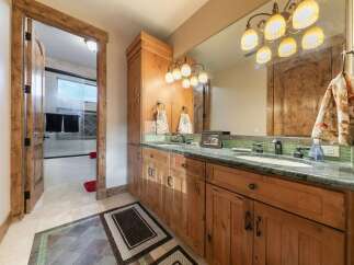 Experience rustic elegance in this charming bathroom, featuring a double vanity with a granite countertop and warm wood cabinetry.