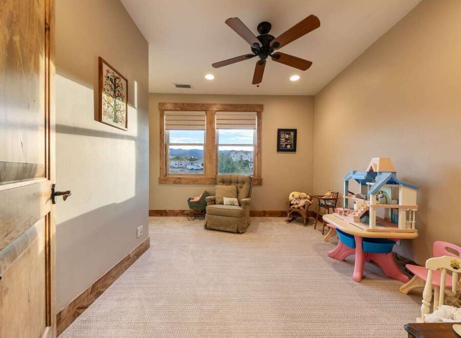 This charming room is perfect for children, featuring a dollhouse, toy table, and comfortable seating.